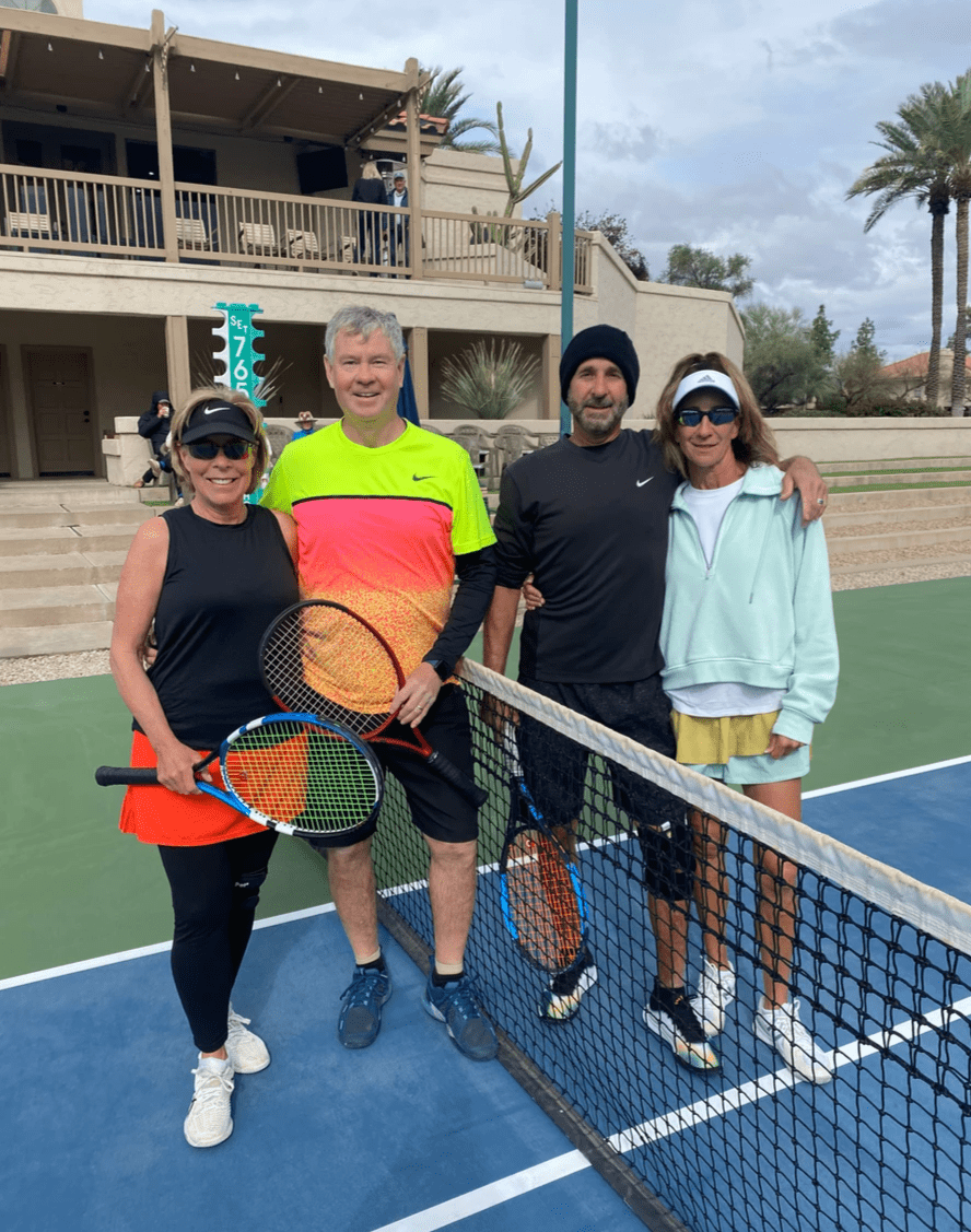 Four players with racquets beside the net at the 2024 over-60 mixed doubles final.