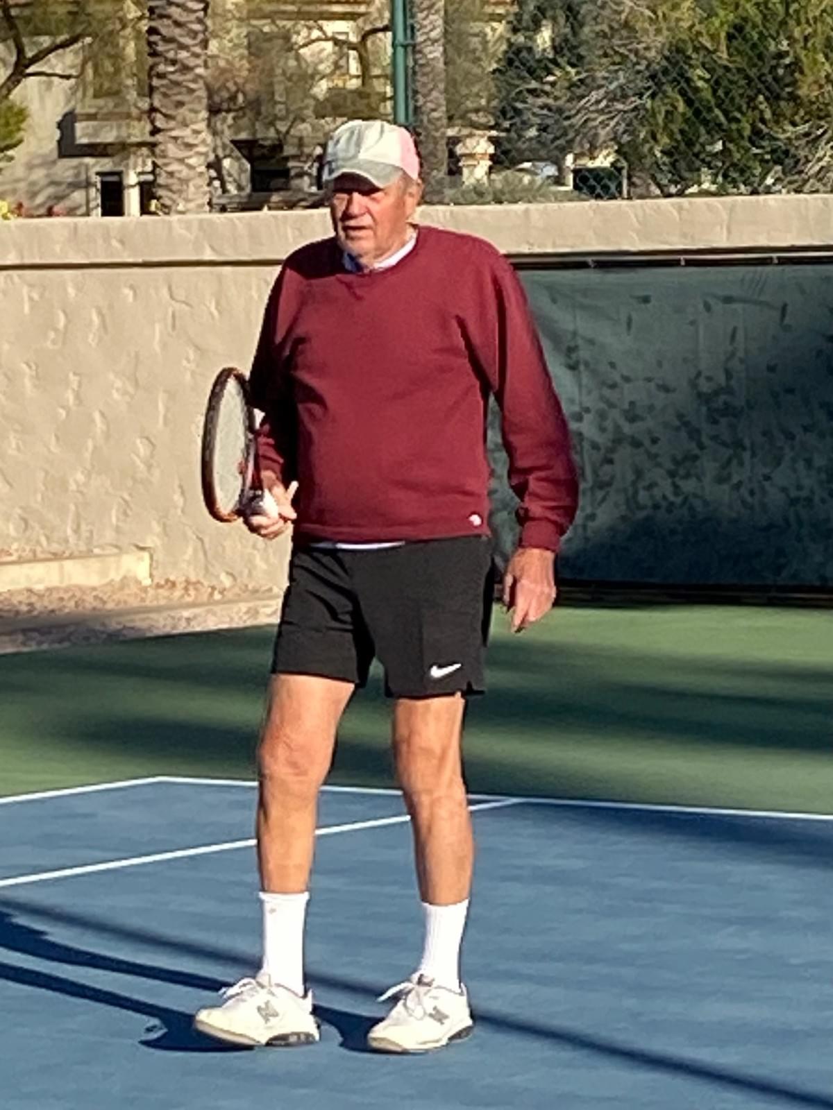 A player in a burgundy top holding a racquet on court during the presidential final.