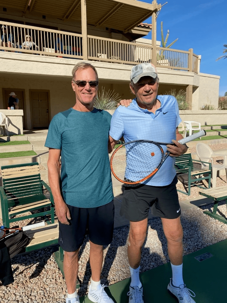 Two presidential champions with a racquet posing beside the clubhouse.