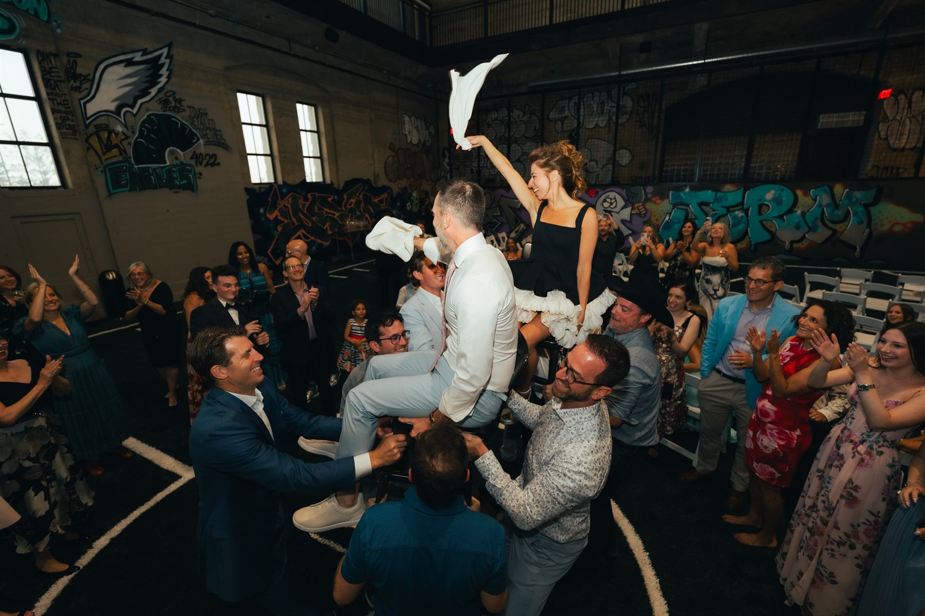 Wedding celebration with guests lifting the couple on chairs at Ballers
