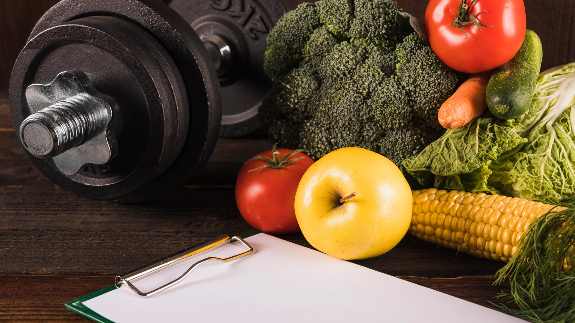 Dumbbell and fresh vegetables representing nutrition and strength training at The Strength Yard in West Palm Beach, FL.