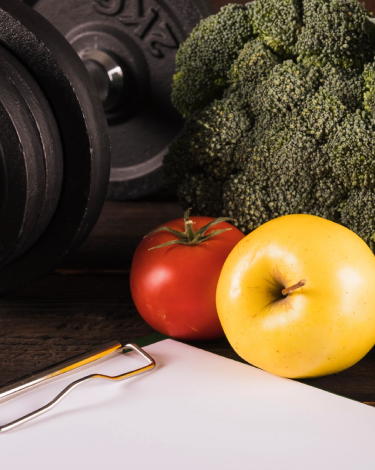 Dumbbell and fresh vegetables representing nutrition and strength training at The Strength Yard in West Palm Beach, FL.