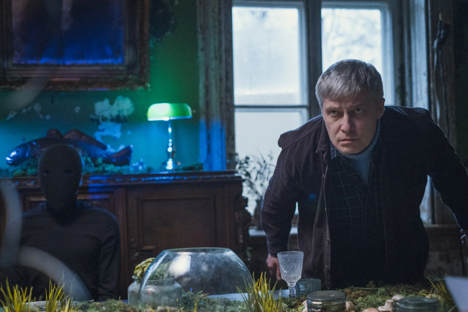 Your Dream – a man stands at a table in a dim room