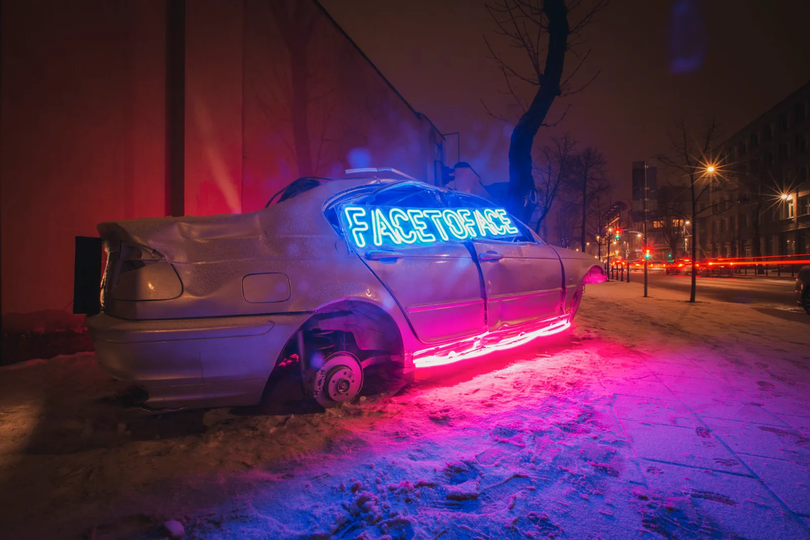 Kosmos Car – a car lit by neon light in a city street at night