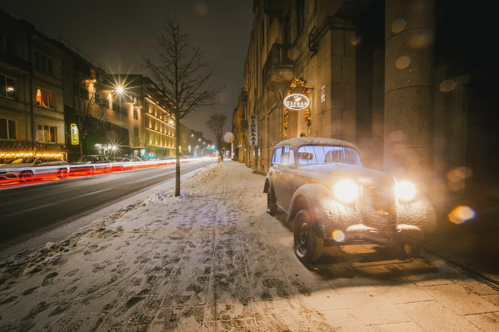 Kosmos Car – a vintage car with headlights on a snowy boulevard at night
