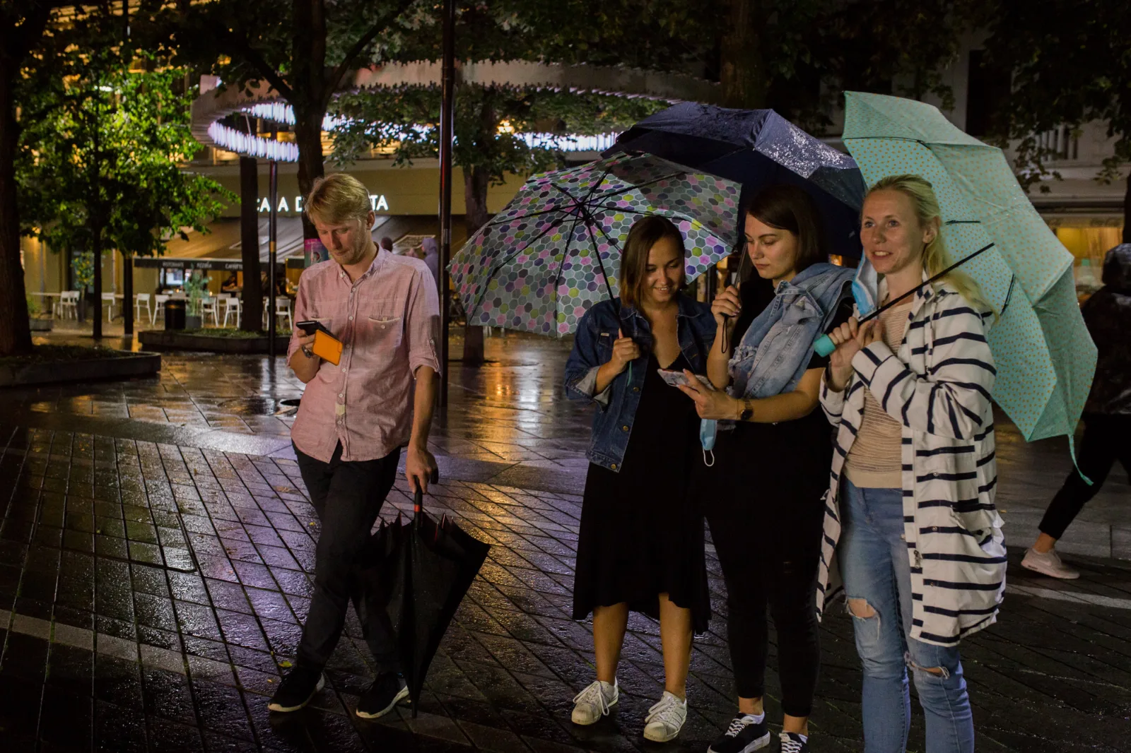 #Protest – spectators with umbrellas look at their phones in a rainy square