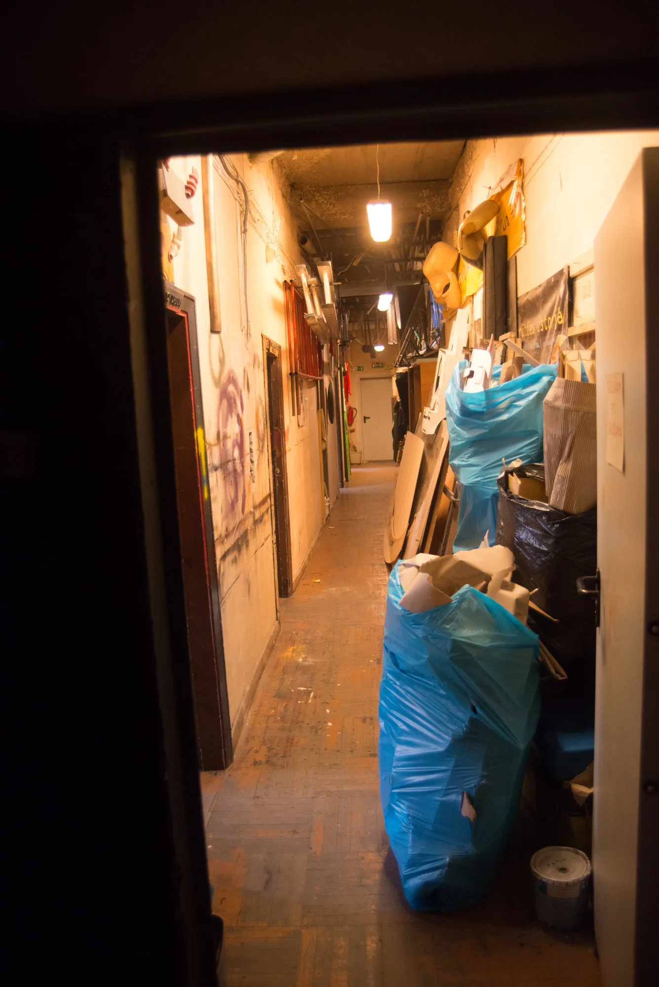 Lila – a narrow corridor full of bags and props seen through a doorway