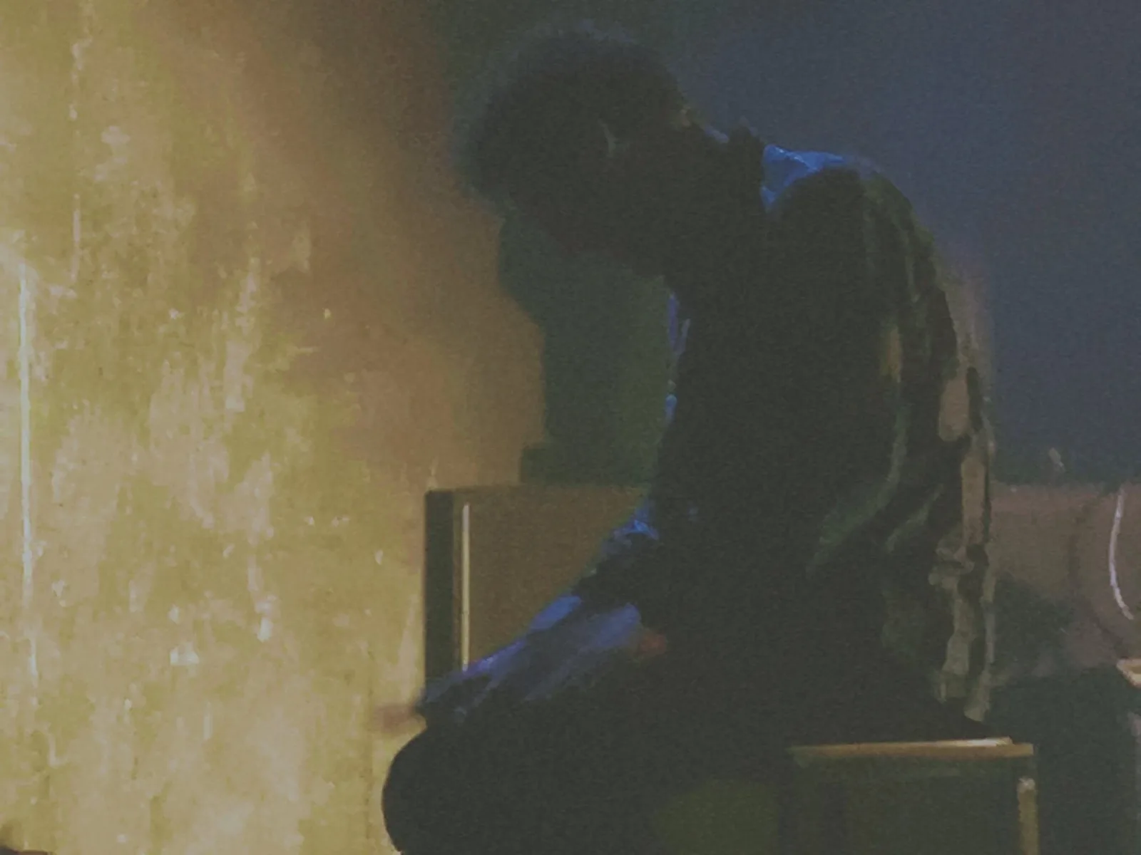 Sonny’s Blues – a man sits hunched over in dim yellow light