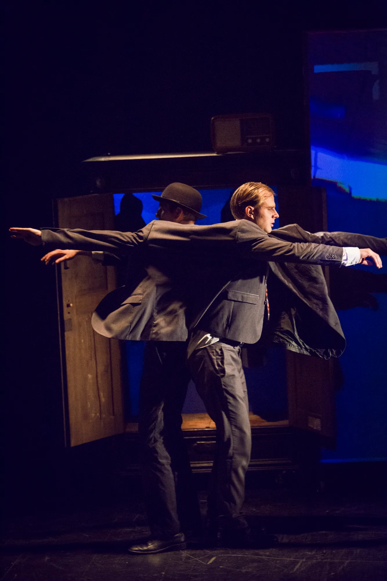 Kafka Insomnia – two men in bowler hats stand back to back with their arms spread wide