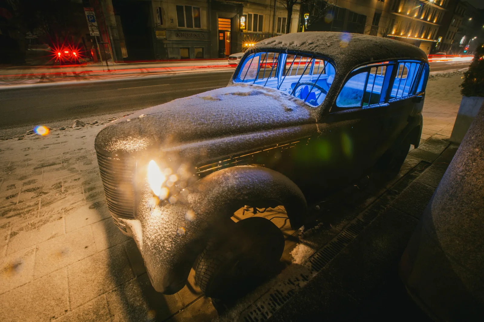 Kosmos Car – a snow-covered vintage car with glowing blue windows on a city street