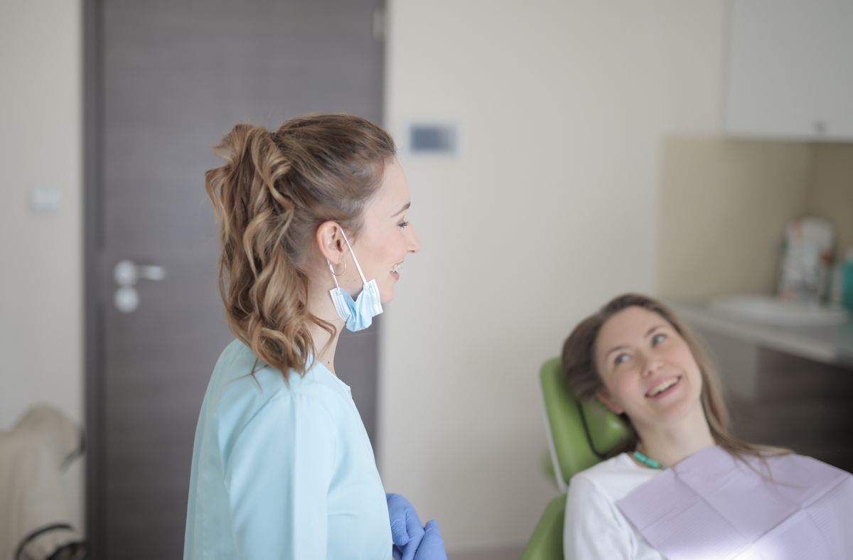 A dentist talking with a patient in a light-filled clinic.