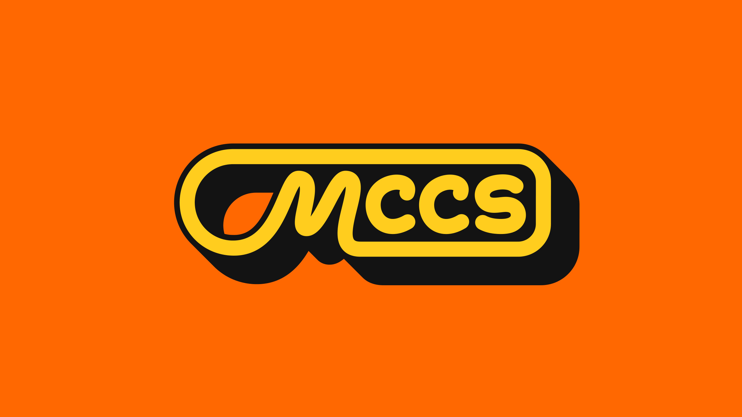 The MCCS icon: yellow letters in a black pill badge, the M’s swoosh looping into its outline