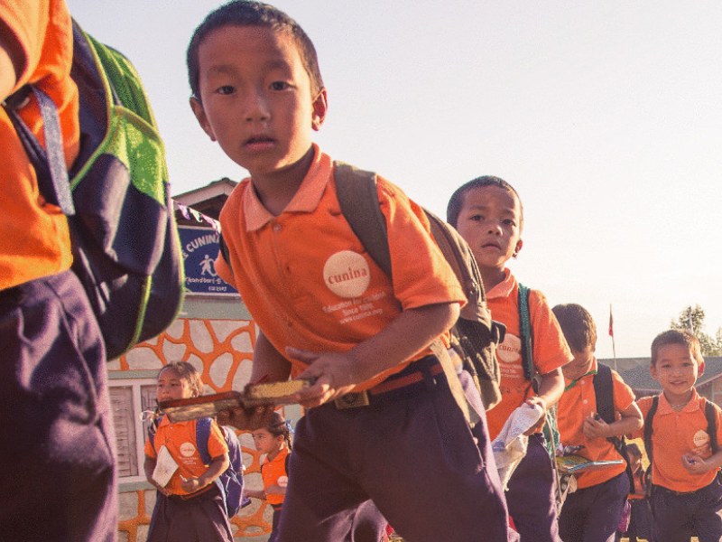 Schoolkinderen in Cunina-uniform lopen in een rij naar de klas