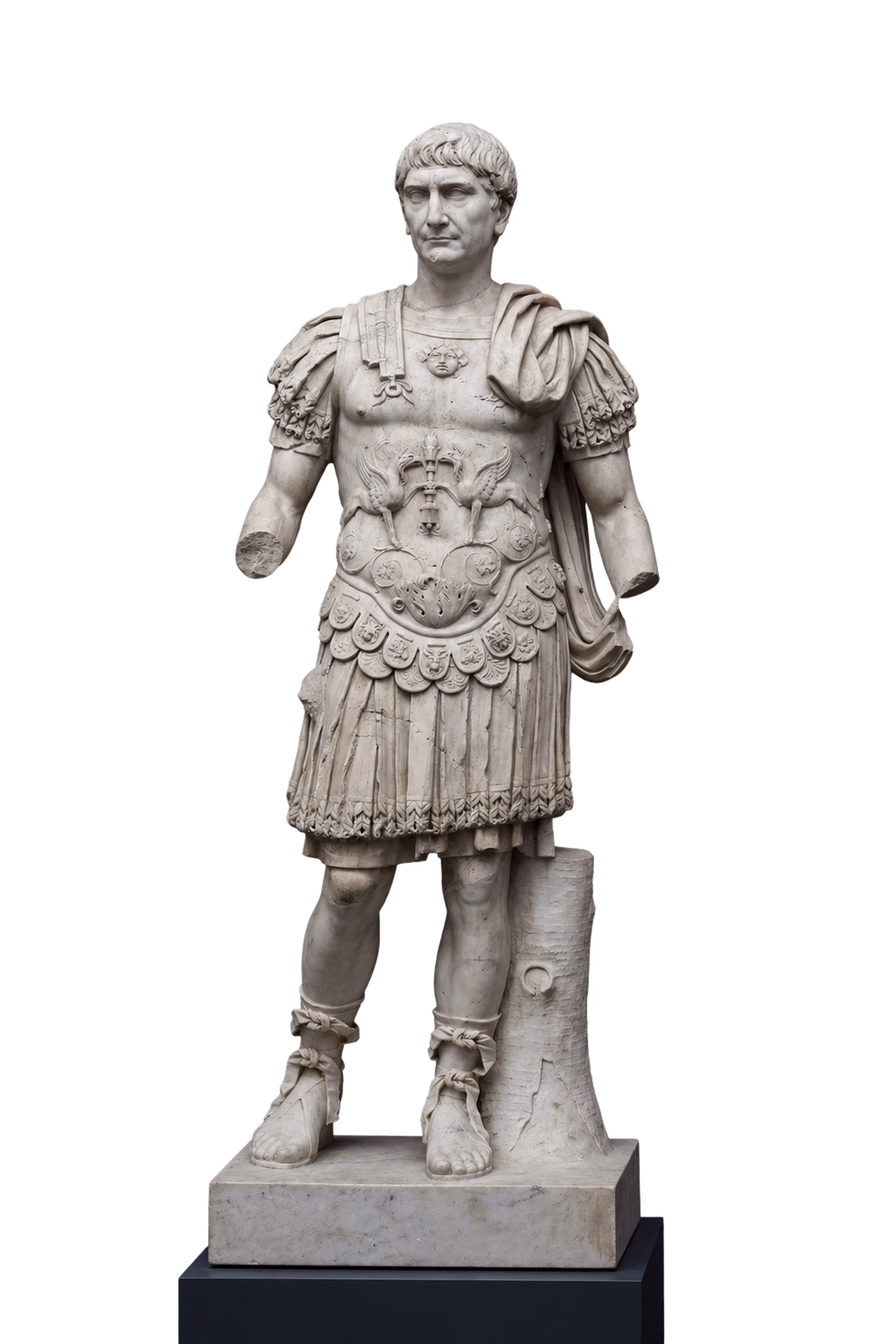 Marmorstatue af en romersk kejser iført en detaljeret brystplade og militærtøj, stående med en alvorlig mine. Armene er delvist beskadiget, og en støttepille er bag den højre ben.