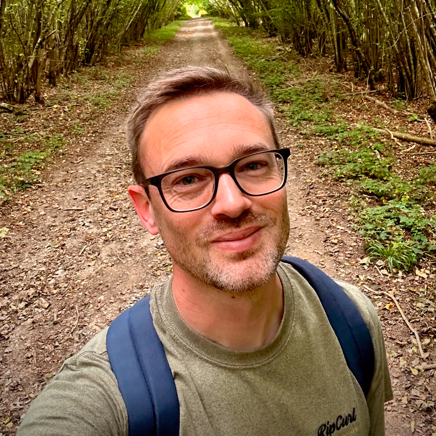 A photo of myself taken while walking a tree-lined woodland path in the South Downs