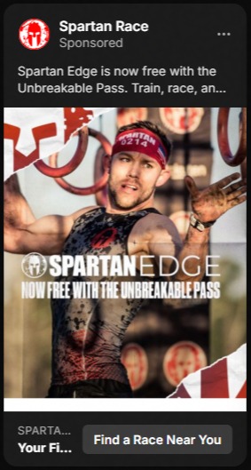 Advertisement for Spartan Race showing a male athlete covered in mud wearing a Spartan headband and athletic gear, reaching out with both hands; text reads 'SPARTAN EDGE NOW FREE WITH THE UNBREAKABLE PASS'.