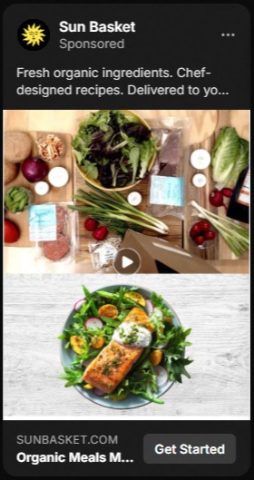 Sun Basket advertisement showing meal kit ingredients on a wooden table including leafy greens, cherry tomatoes, green onions, and seasoning packets, and a plated dish with cooked salmon, greens, and sliced radishes on a gray plate.