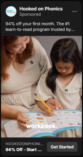 A woman and a young girl both wearing cream-colored tops work together on a phonics workbook, with the girl holding a pencil and focusing on the pages.