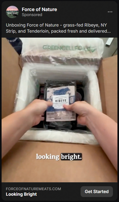 Person unpacking a delivery box with insulated packaging, holding a vacuum-sealed package labeled 'Force of Nature Ribeye,' with the text 'looking bright' visible on the box flap.