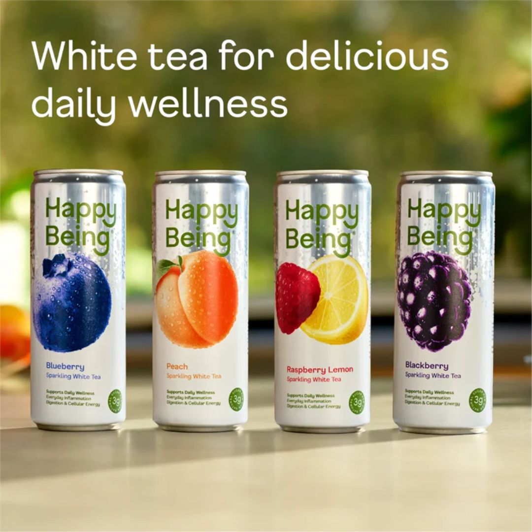 Four cans of Happy Being sparkling white tea in flavors blueberry, peach, raspberry lemon, and blackberry, with text above saying 'White tea for delicious daily wellness.'