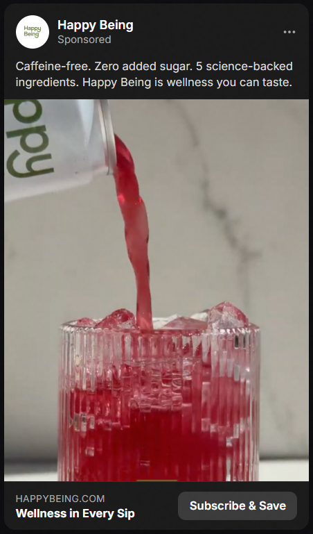 Red beverage being poured from a cup into a clear glass filled with ice, with text about Happy Being caffeine-free wellness drink.