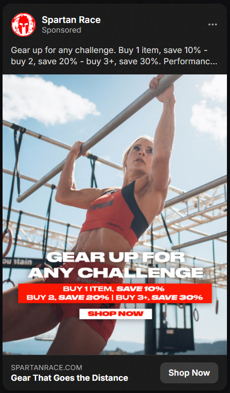 Athletic woman in red Spartan race gear doing pull-ups on an outdoor obstacle course with a clear sky background, promoting Spartan Race gear with text offering discounts for multiple item purchases and a shop now call to action.