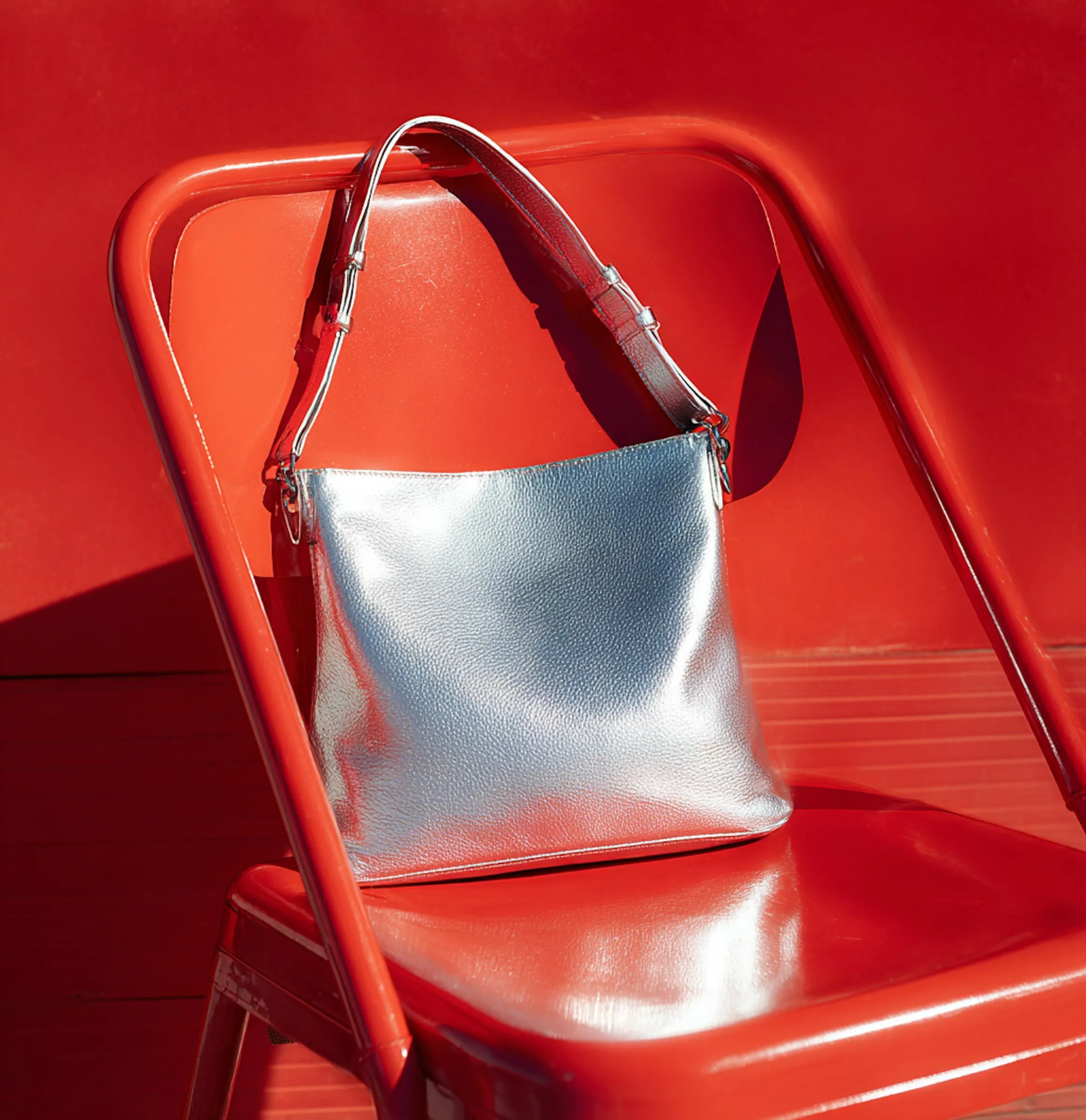 A silver purse sitting on top of a red chair.