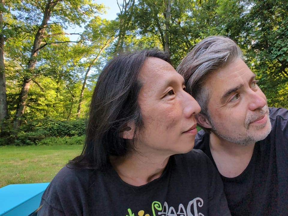Me and Joon sitting in a sunny setting next to woods, looking into the distance, contemplating a future where my age starts with a 5, the first time that's happened since I was 5.
