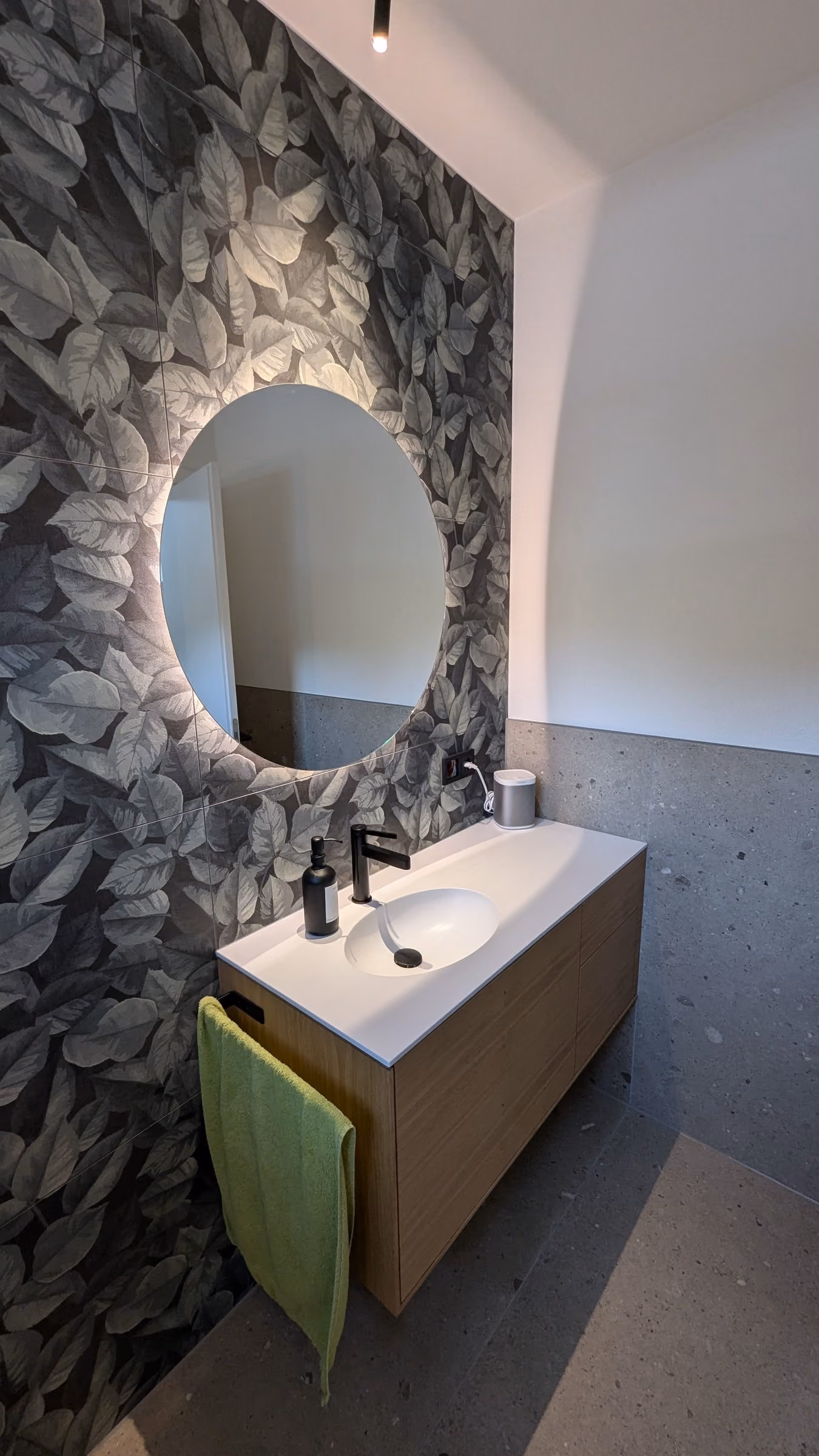 Waschtisch vor einer Natursteinwand mit rundem Spiegel