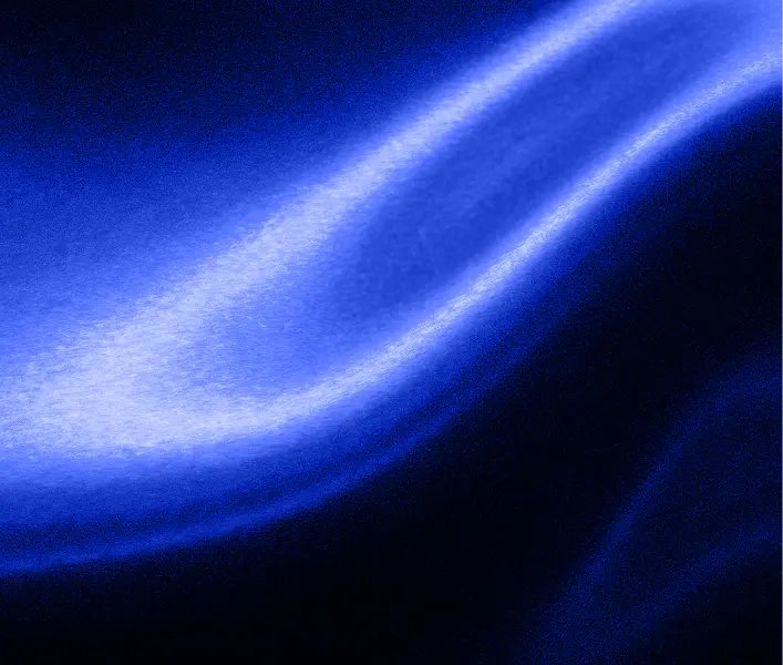 Close-up of shiny, smooth blue satin fabric with light reflections creating flowing curves.
