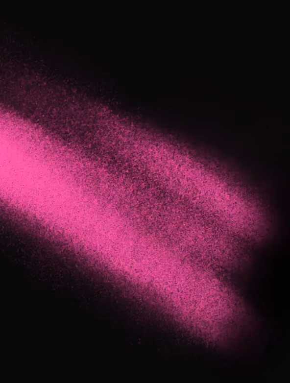 Spray of bright magenta powder against a black background, creating a cloud-like effect with fine particles dispersed outward.