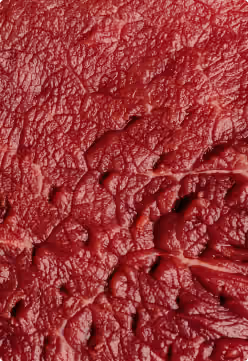 Close-up van rauw rood vlees met zichtbare weefselstructuur.