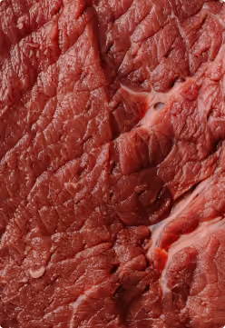 Close-up van een rauw stuk rood vlees met zichtbare vezelstructuur en fijne lijnen.