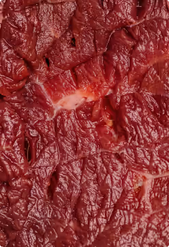Close-up van rauw rood vlees met zichtbare vezels en textuur.