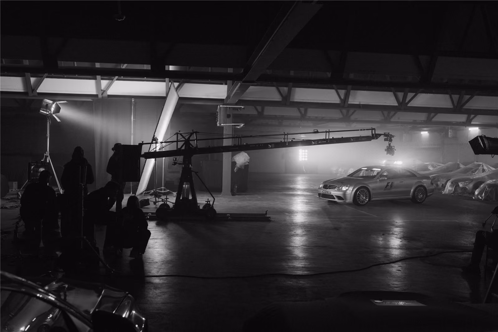 Film crew with a camera crane on a car shoot in a hangar