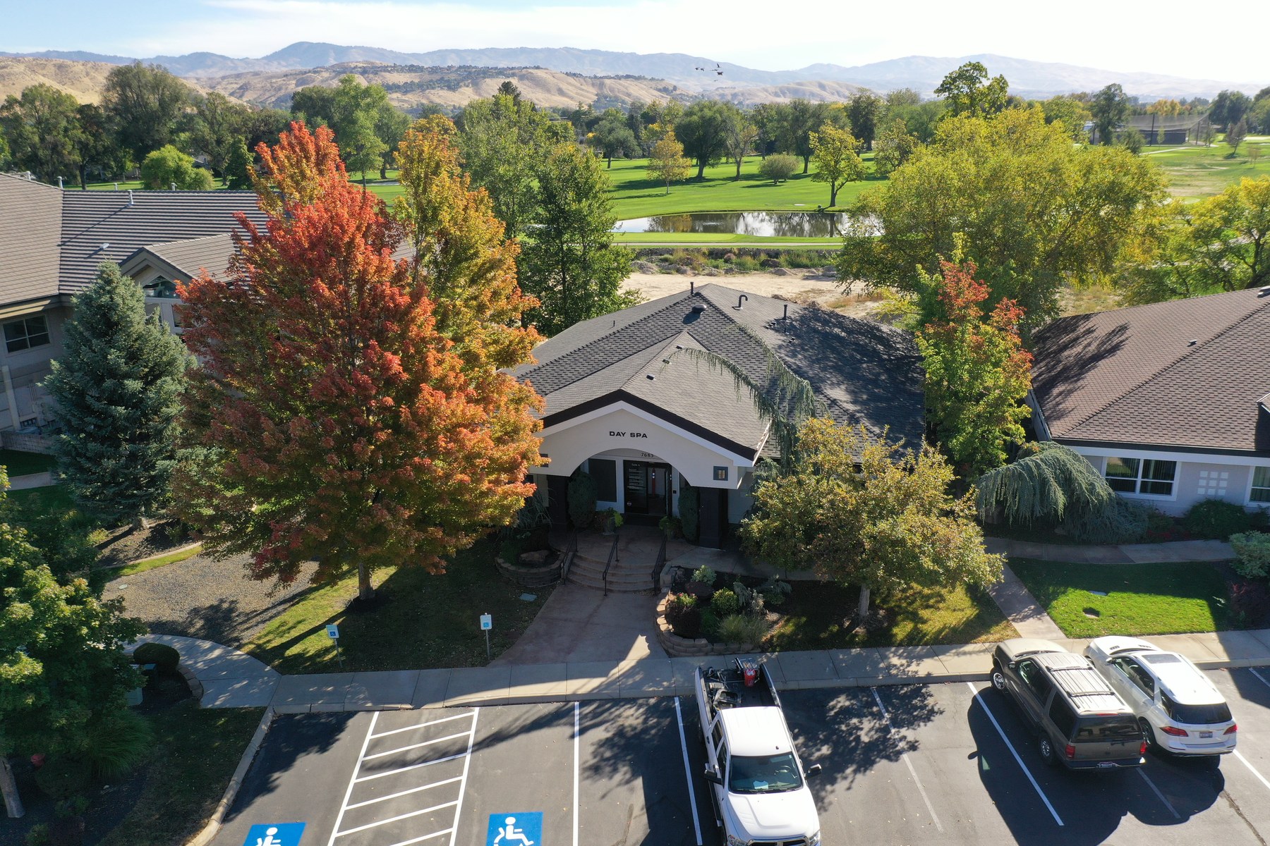 Aerial view of the W Riverside Dr day spa beside the golf course, with the Boise foothills behind