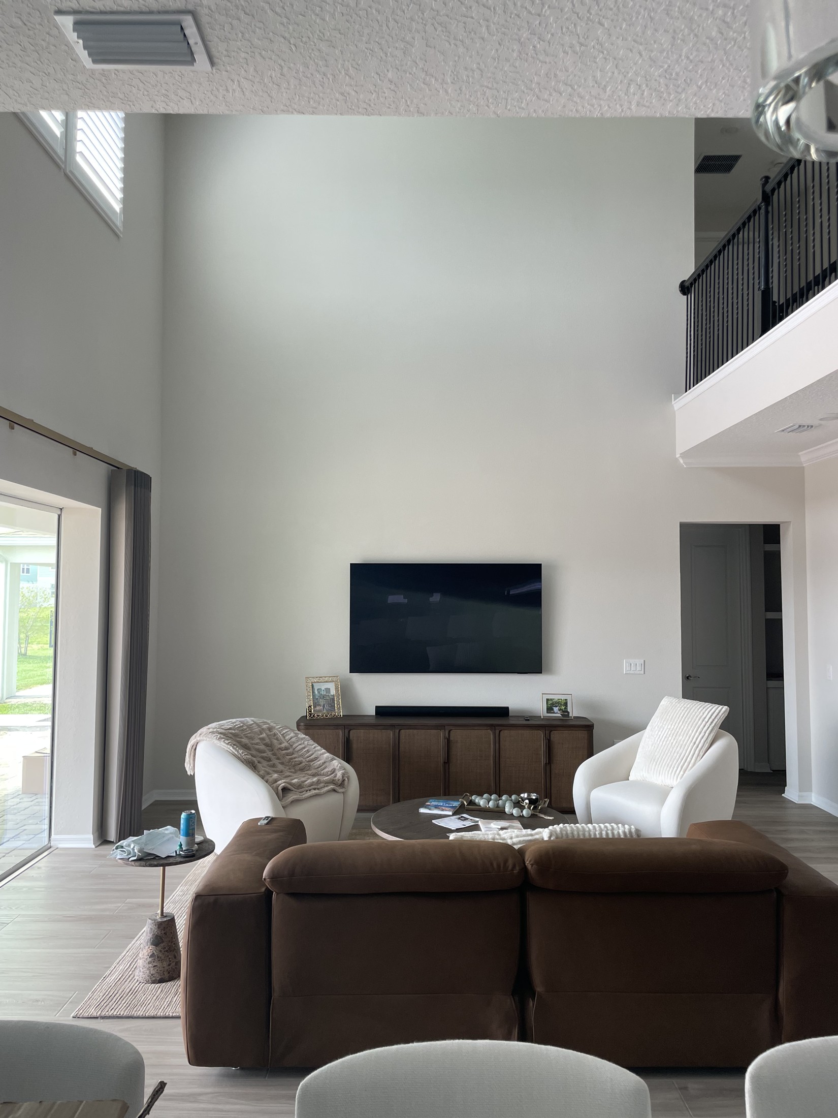 Original double-height living-room wall with a mounted television and freestanding console