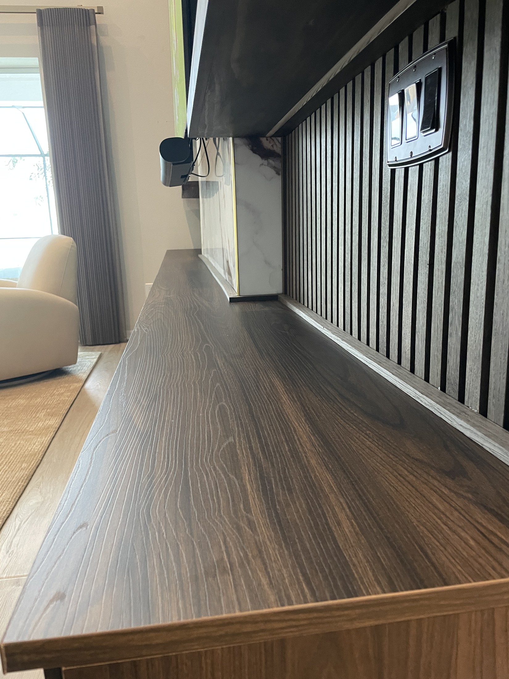Close-up of the dark wood-look cabinet top meeting the slatted wall and central finish