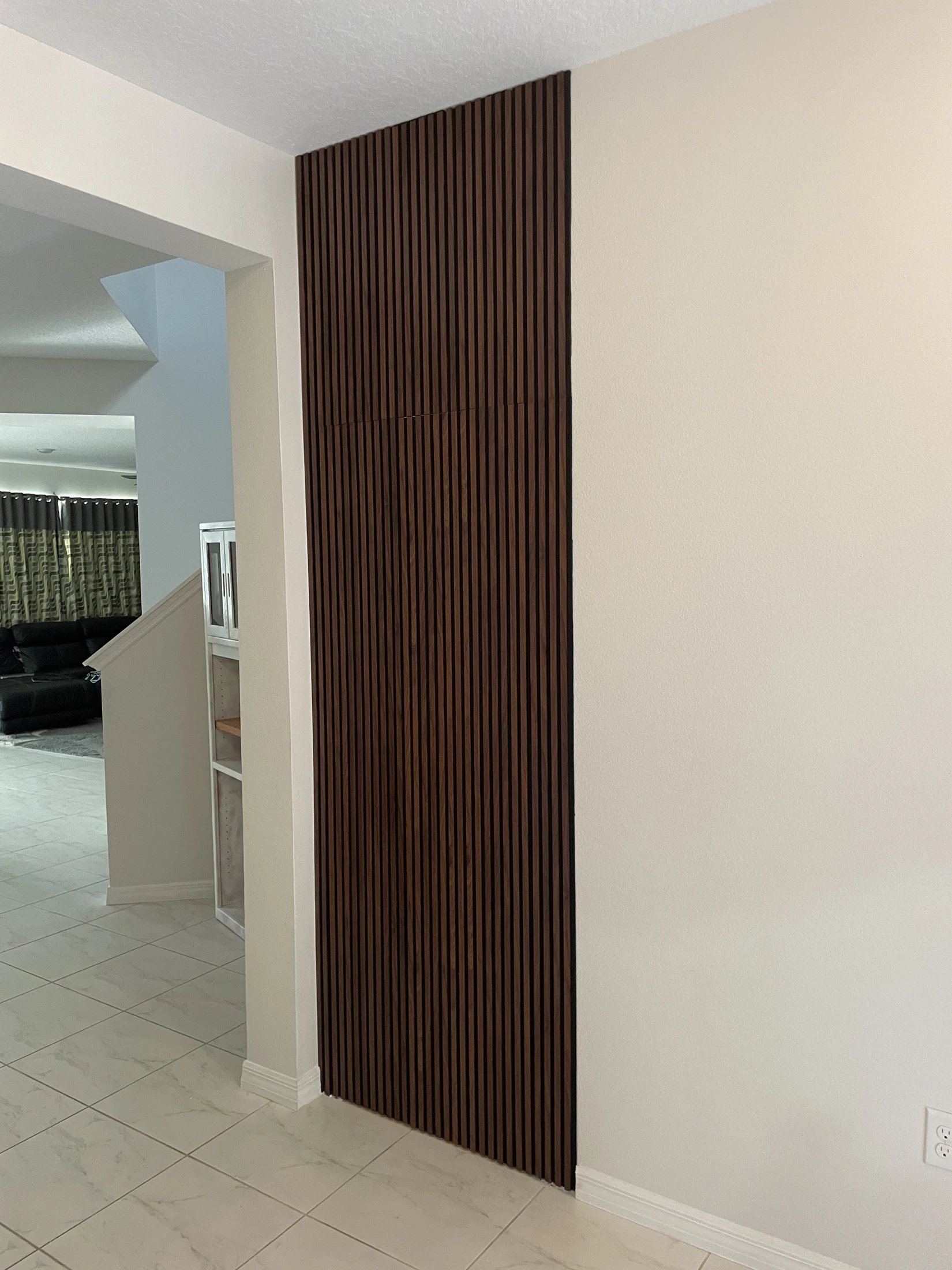 Finished dark wood-look slat feature concealing a doorway beside a staircase