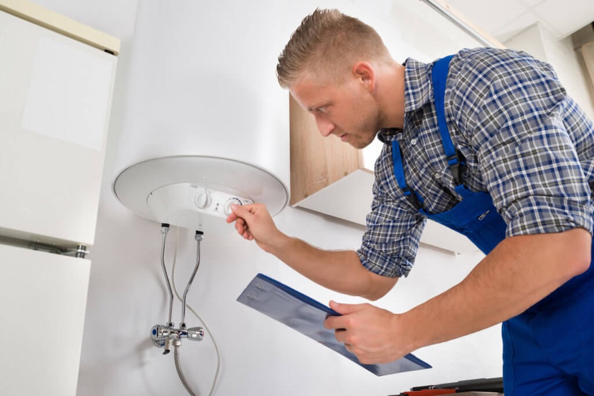 Technician inspecting a residential water heater in a Minnesota basement