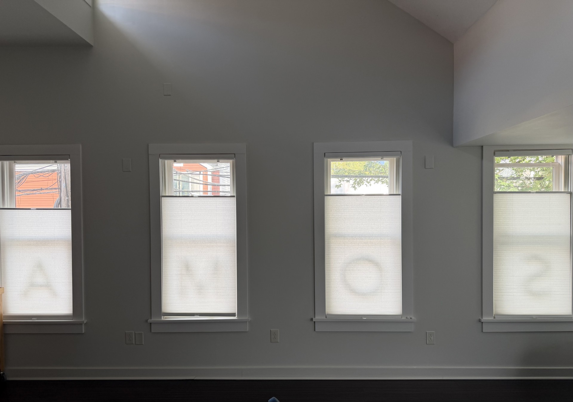 Seating area in the Madrona office, with four tall windows under sheer shades, pale walls, and dark wood floors