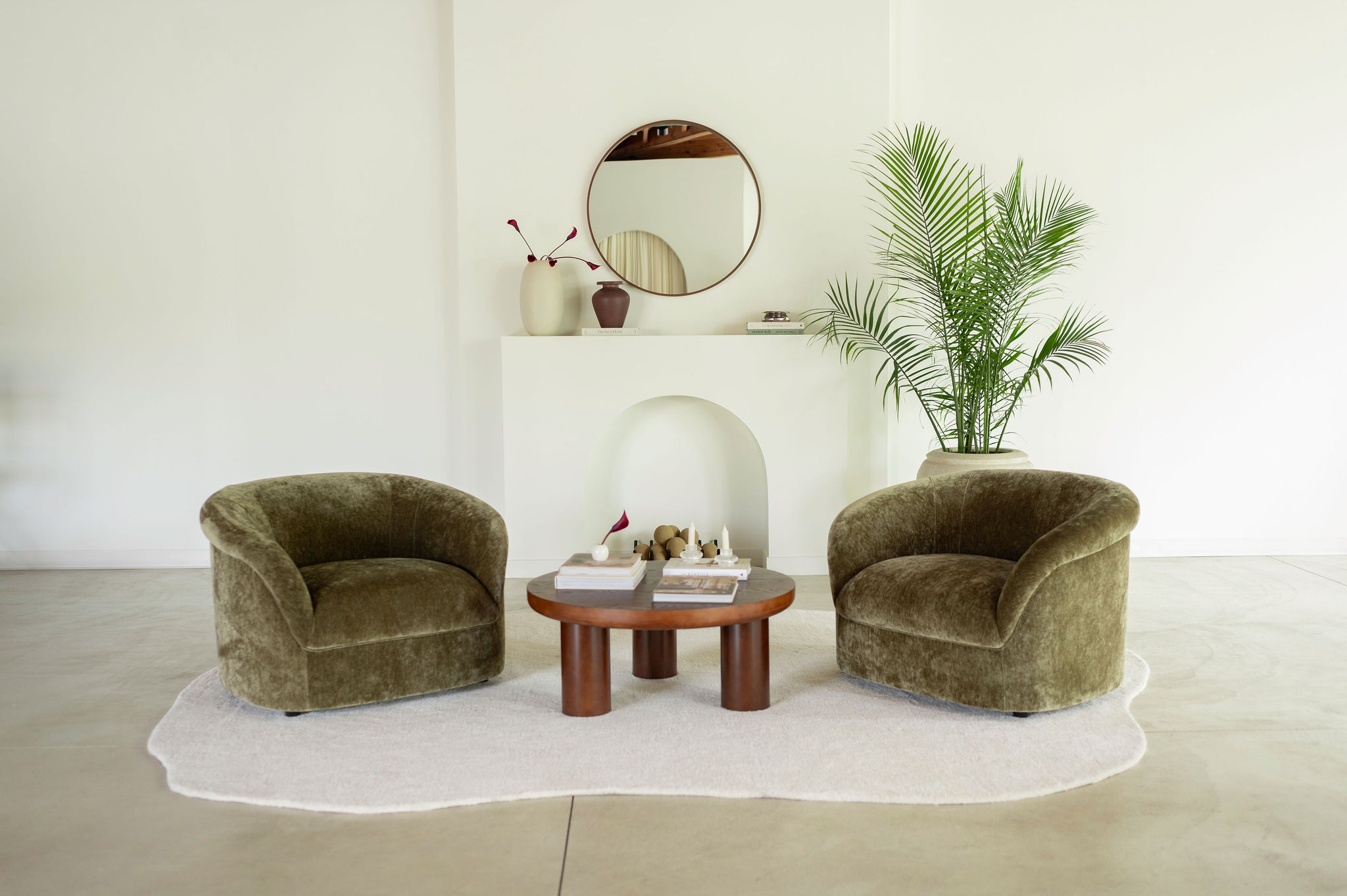 Two olive velvet chairs around a walnut coffee table in the studio