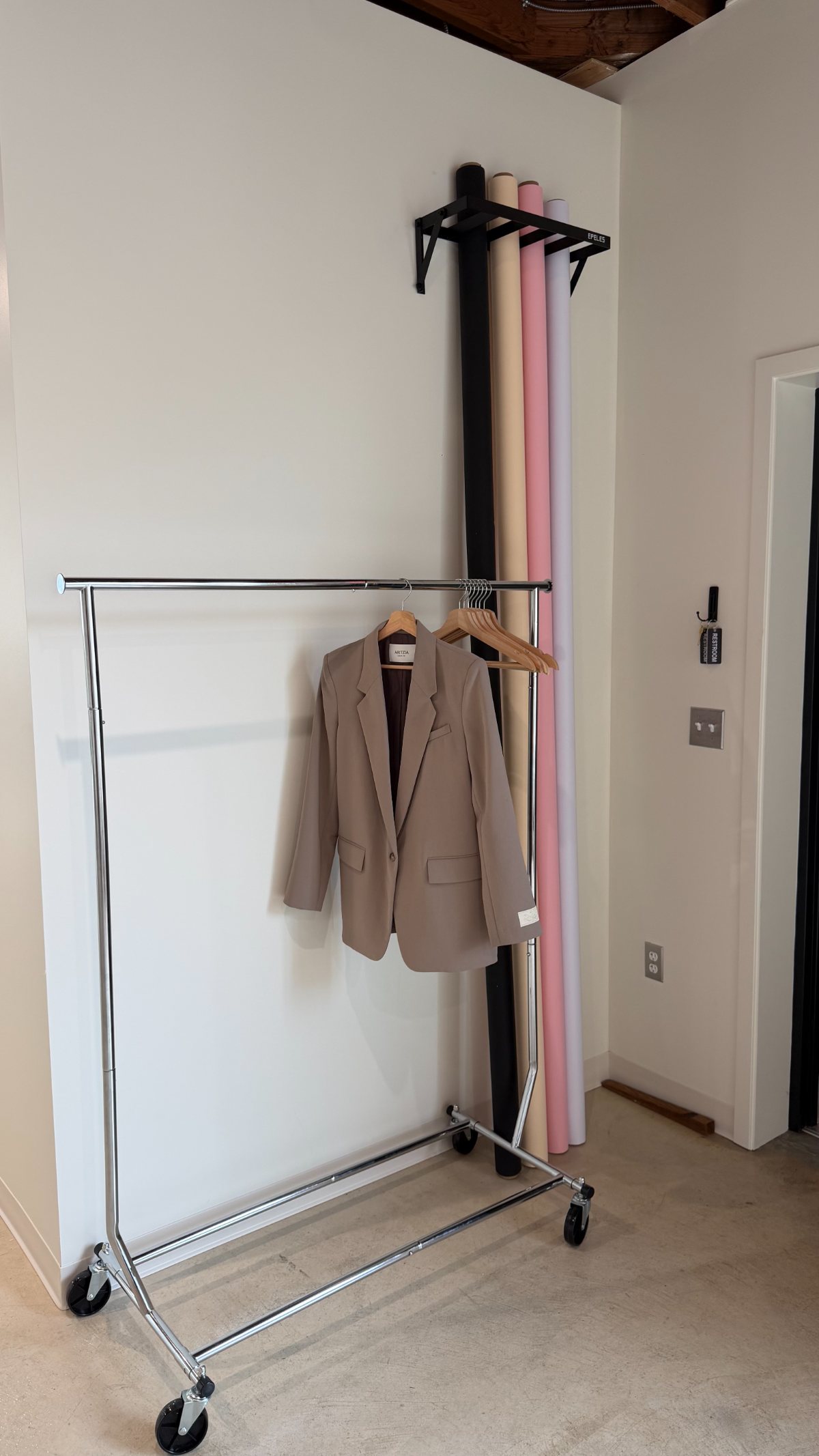 Rolling clothing rack with wooden hangers beside the seamless backdrop rolls