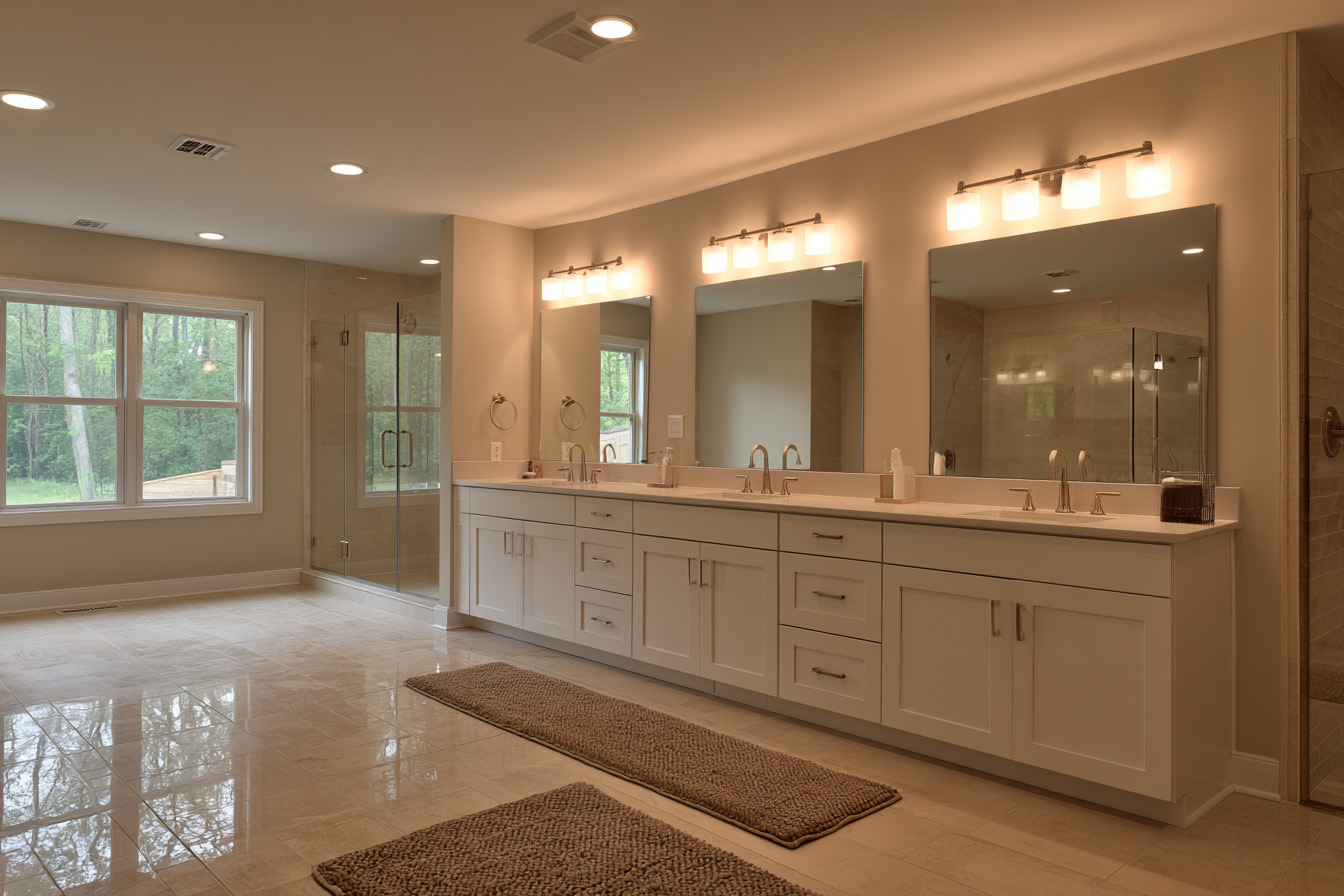 A long double vanity with multiple mirrors, wall sconces, and warm lighting, with a glass shower visible in the reflection.