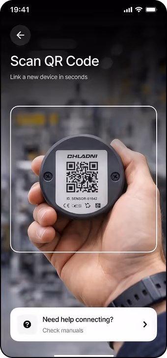 Smartphone screen showing a QR code scanner app frame focusing on a round sensor device labeled 'CHILARDI' with a QR code and text below reading 'ID SENSOR - 01042'. The app interface includes the prompt 'Scan QR Code Link a new device in seconds' and a help button labeled 'Need help connecting? Check manuals'.