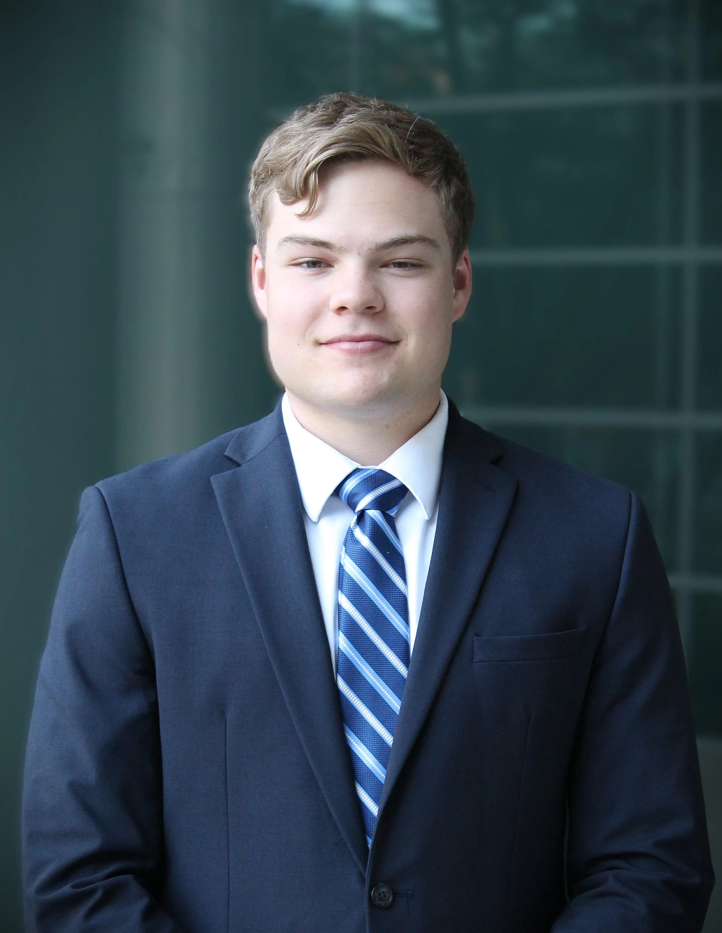 Portrait of Grant Hastings in a navy suit and tie
