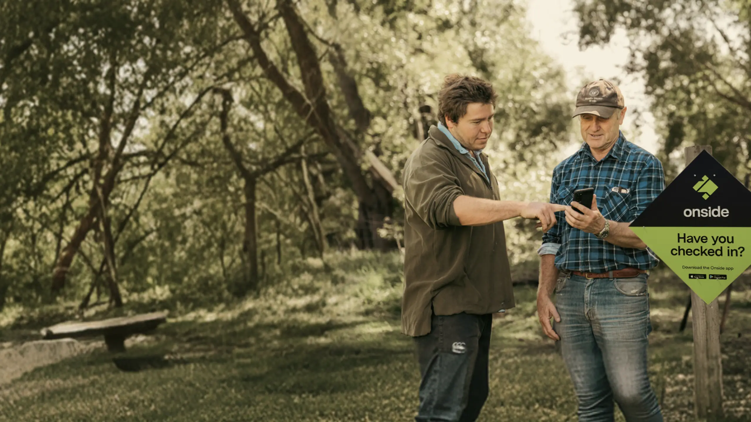 Two people using Onside beside a rural property check-in sign.