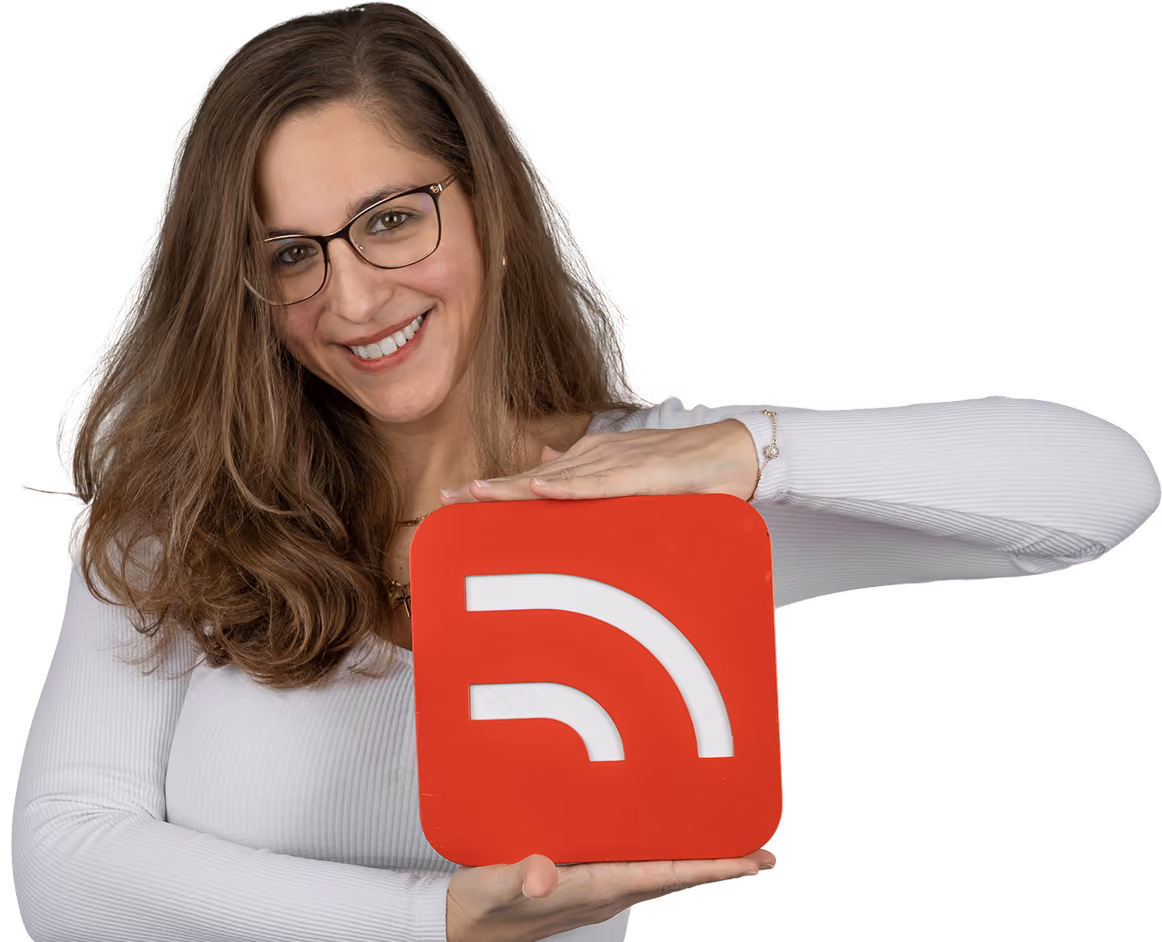 Femme souriante avec des lunettes et un pull blanc tenant une plaque rouge avec une icône blanche de flux RSS.