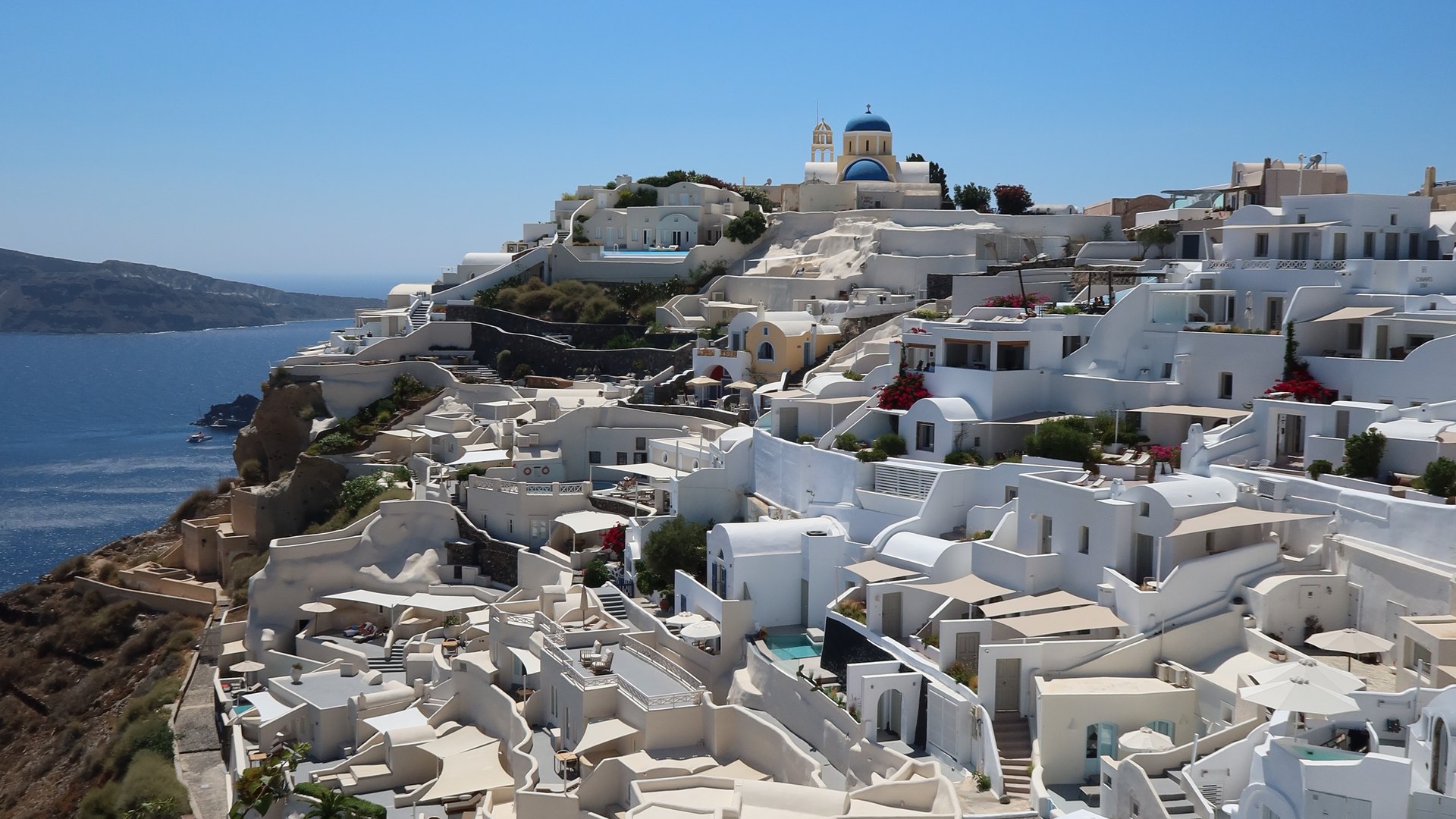 White houses and a blue-domed church on the cliffs of Oia, Santorini, above the caldera