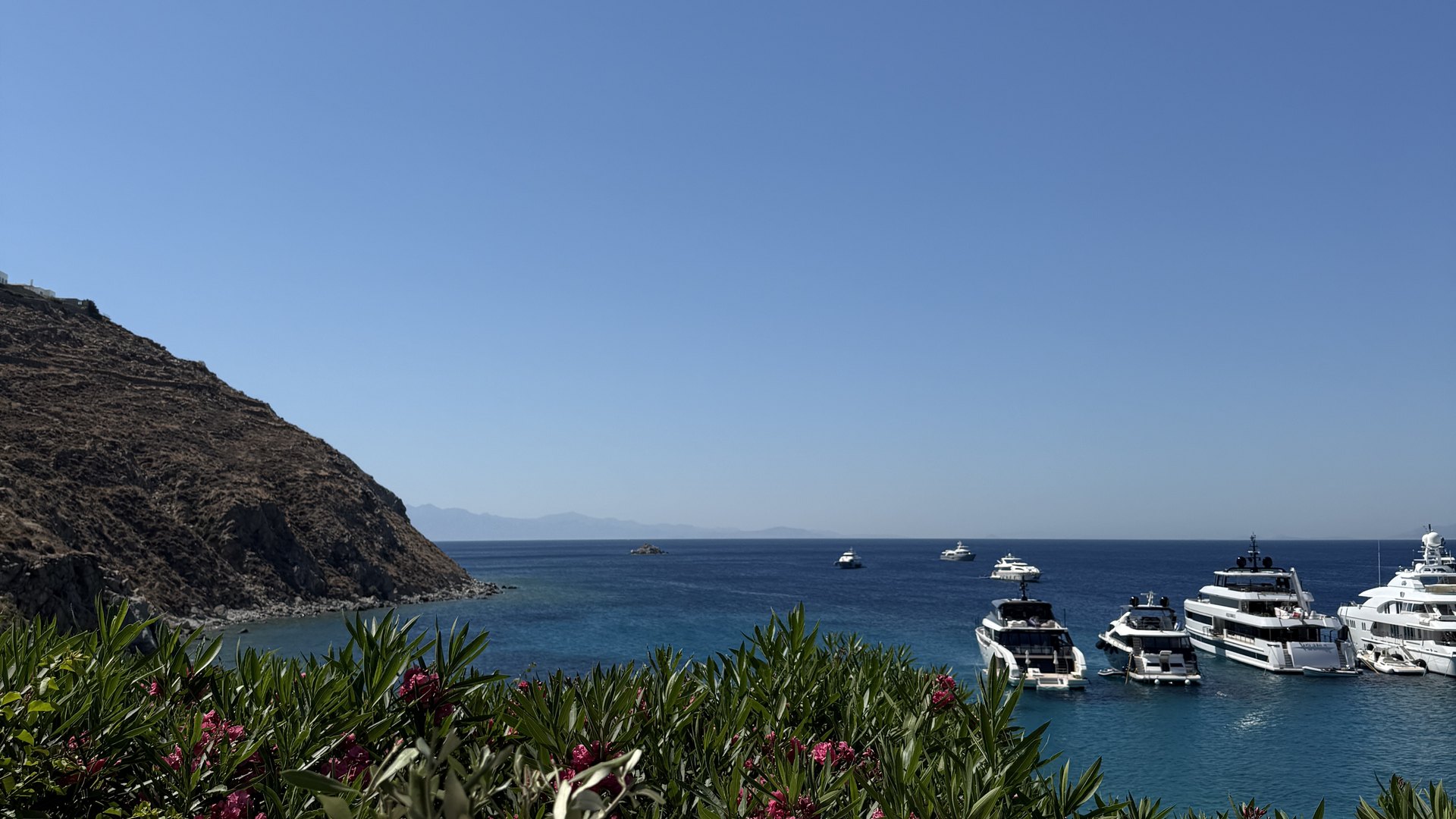 Yachts anchored in a bay on the south coast of Mykonos, with pink oleander in the foreground